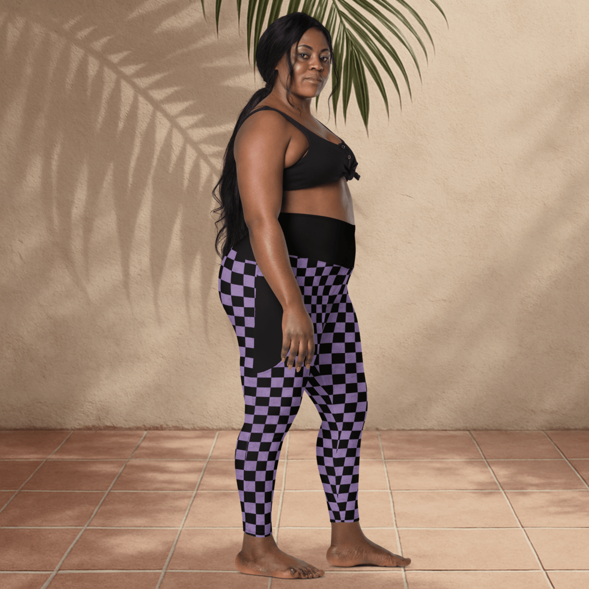 Woman wearing black and purple checkered leggings against a beige wall.