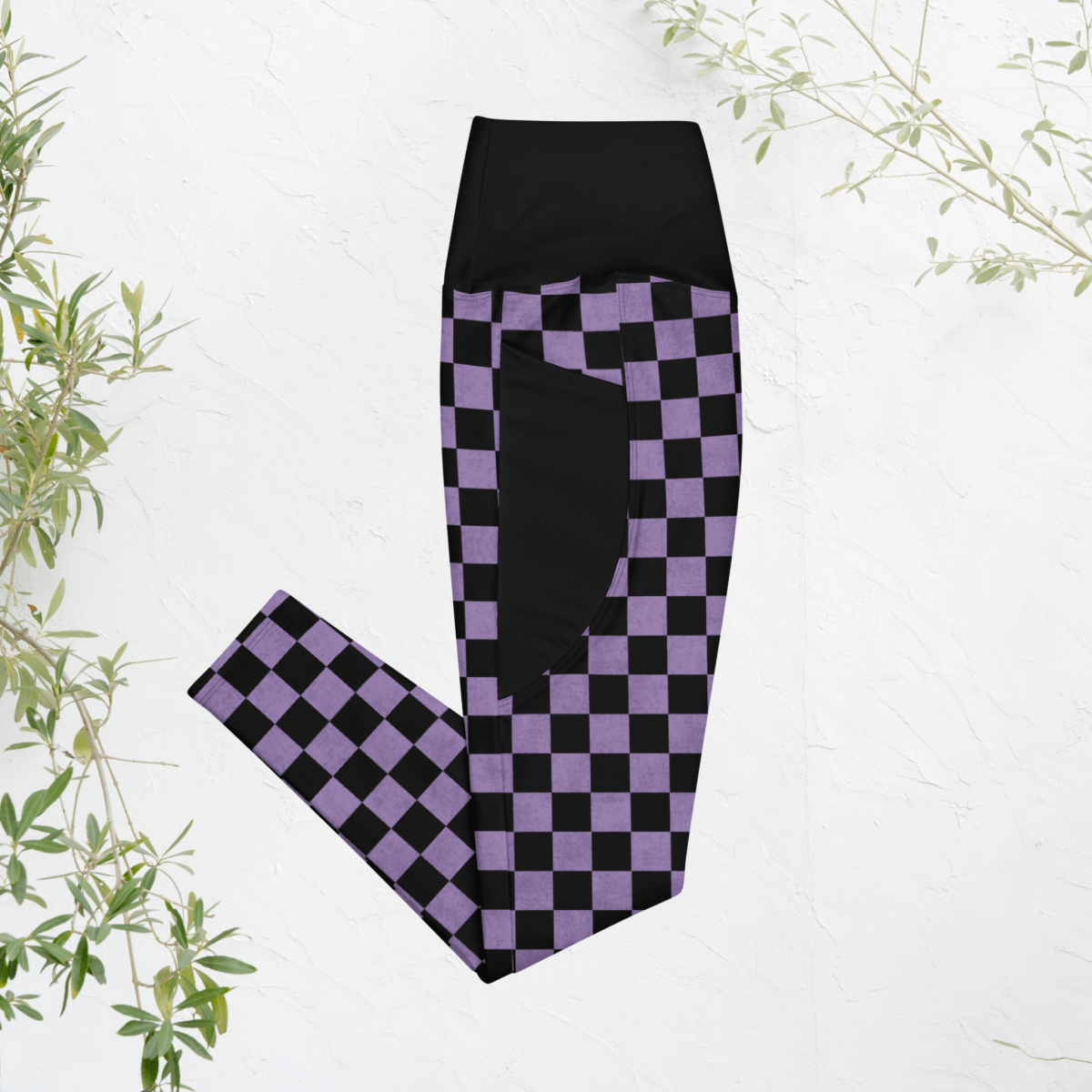 Black and purple checkered leggings on a white background with green leaves.
