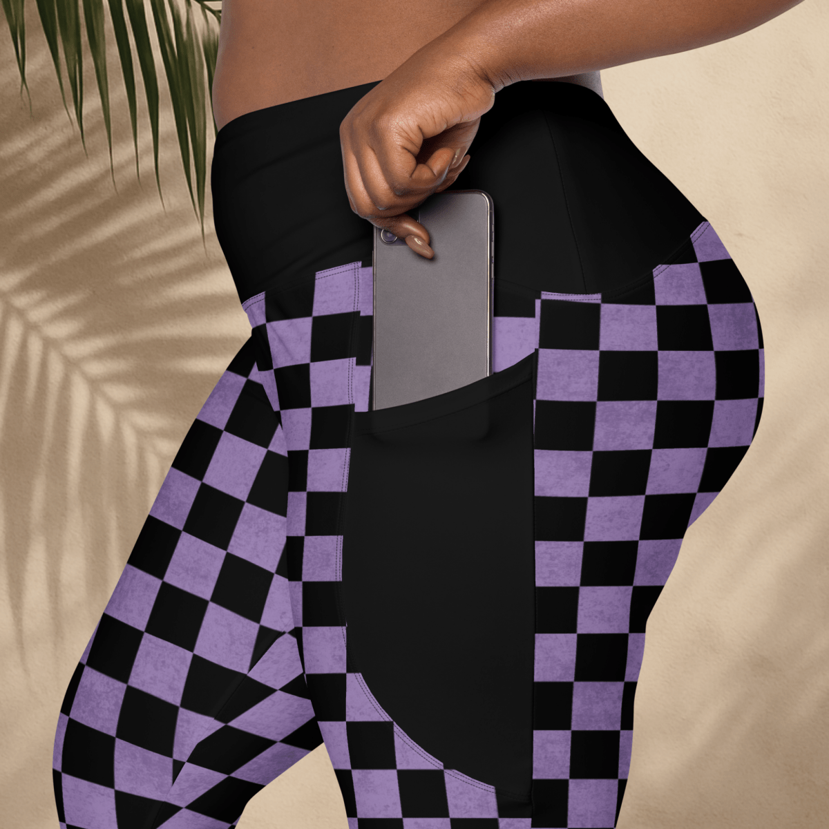 Person wearing black and purple checkered leggings with a pocket holding a phone.