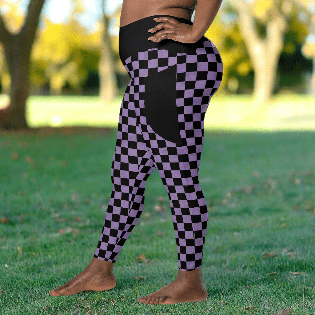 Person wearing black and purple checkered leggings standing on grass with blurred trees in the background