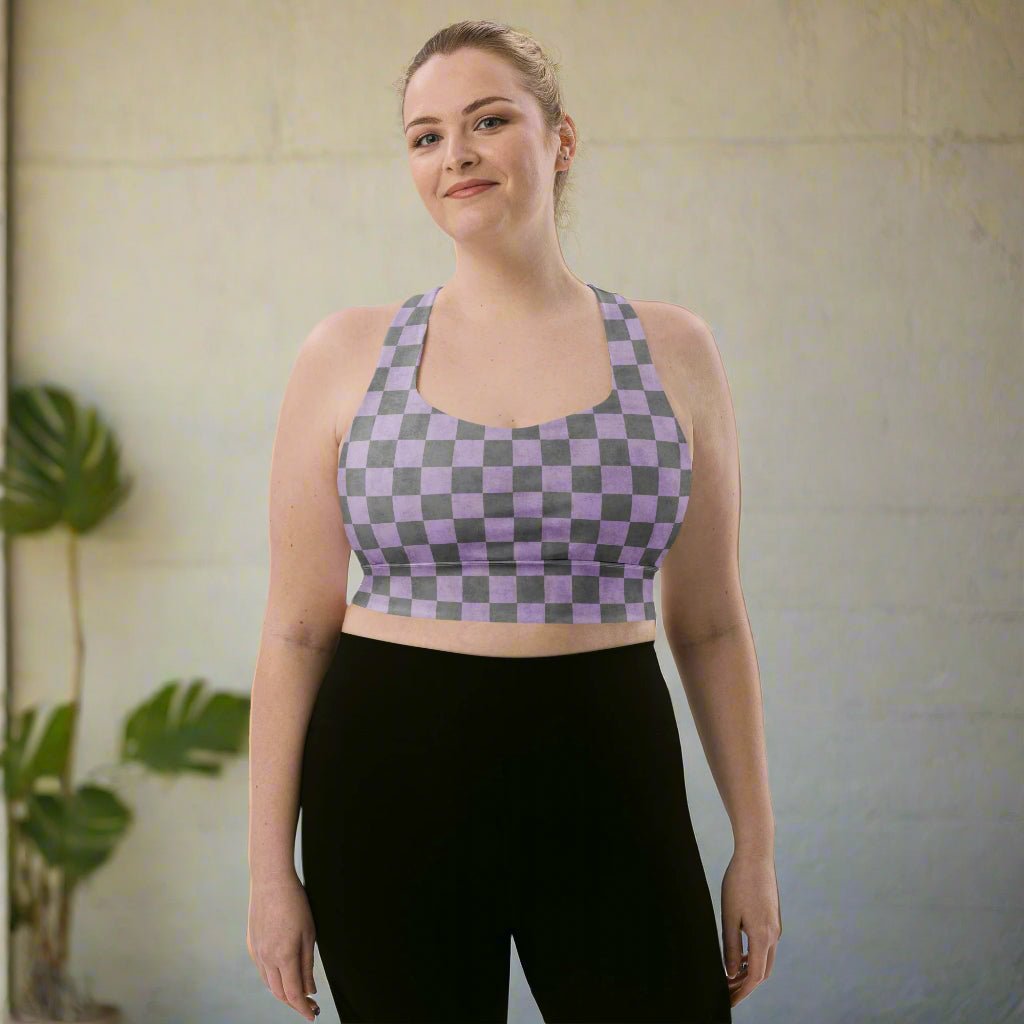 Woman wearing a checkered sports bra and black leggings against a neutral wall.