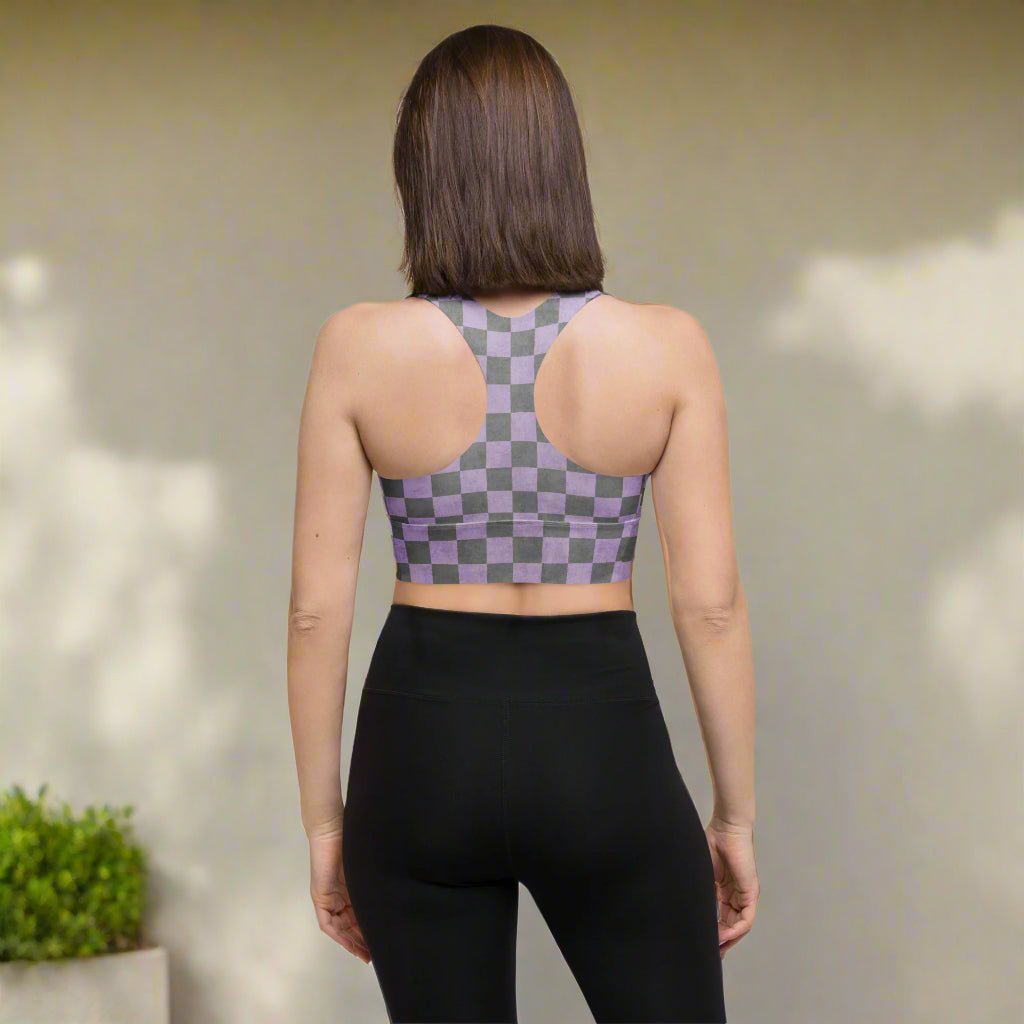 Person wearing a checkered sports bra and black leggings against a neutral wall.