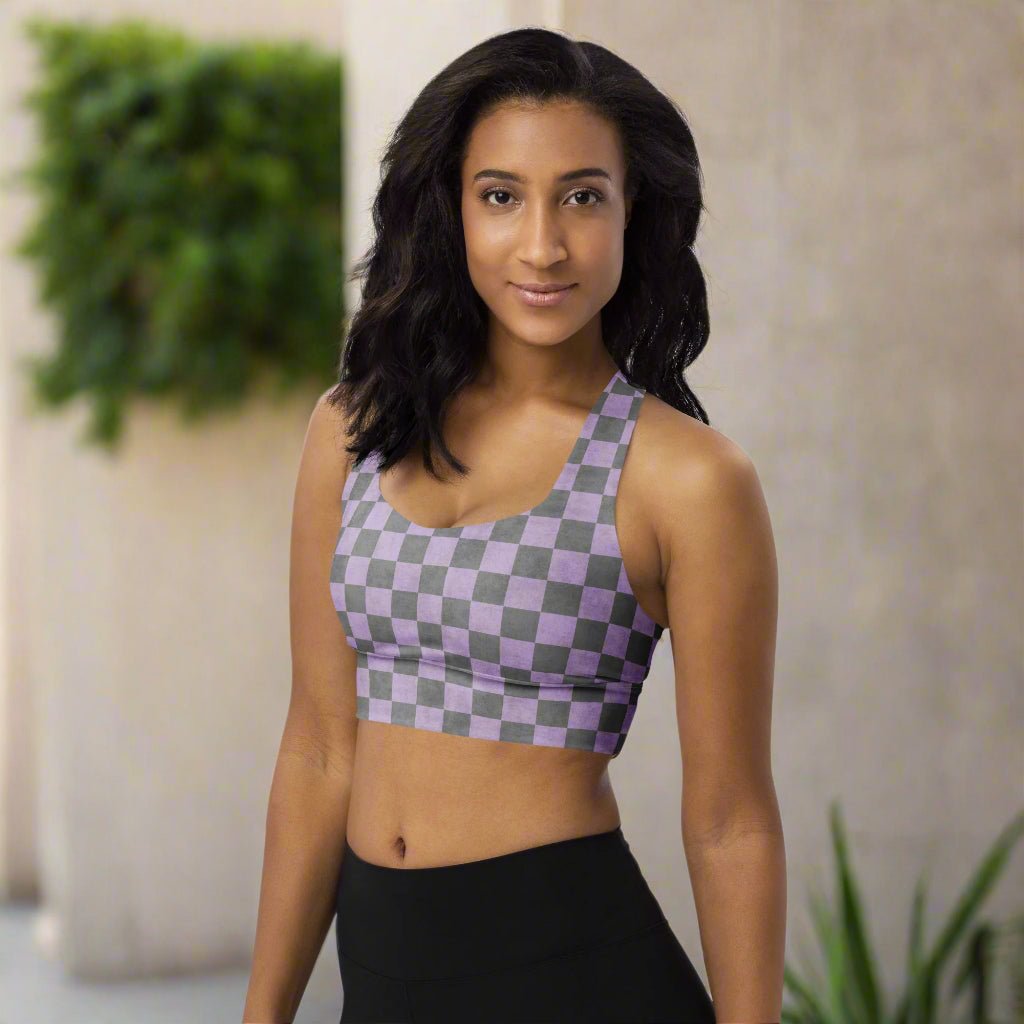 Woman wearing a checkered sports bra and black leggings in an indoor setting with plants.