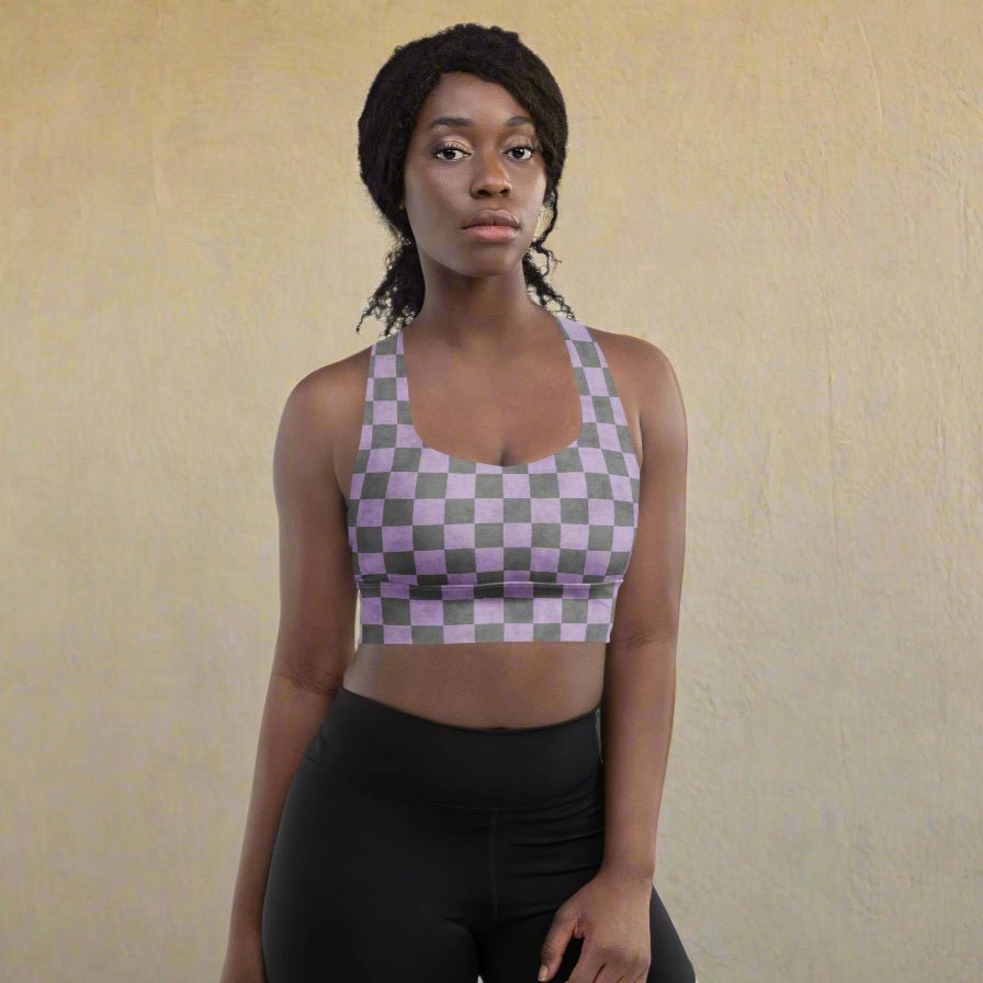 Woman wearing a checkered sports bra and black leggings on a beige background