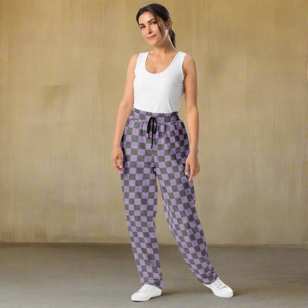 Woman wearing a white tank top and purple checkered pants on a beige background