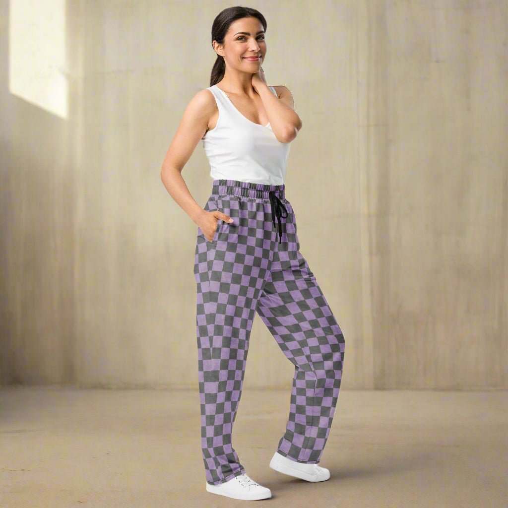 Woman wearing purple checkered pants and a white top on a neutral background