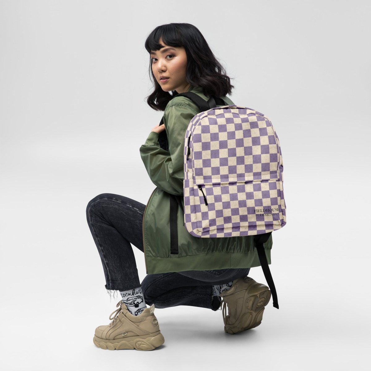 Person wearing a green jacket and checkered backpack on a white background