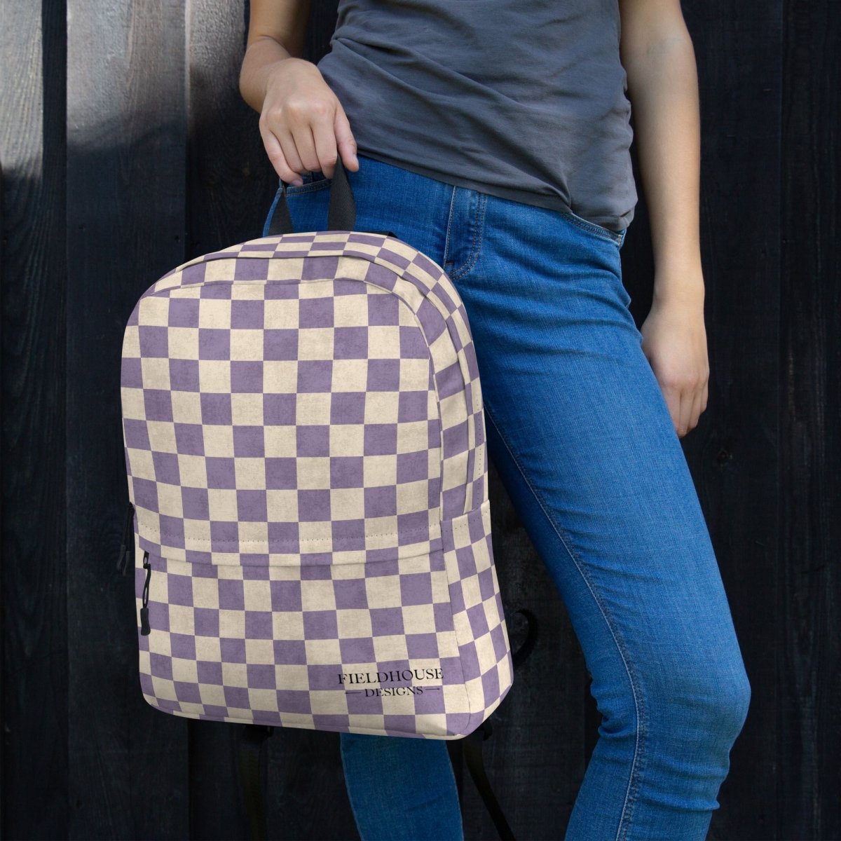 Person holding a checkered backpack with a dark background