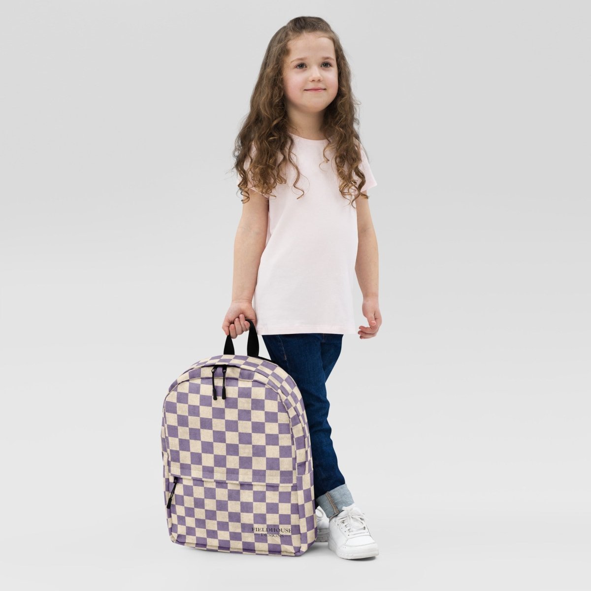 Child holding a checkered backpack against a plain background