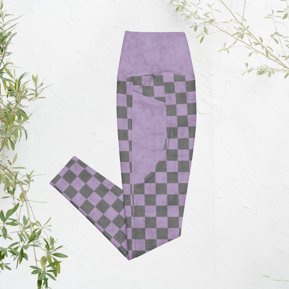Purple and gray checkered leggings on a white background with green leaves.