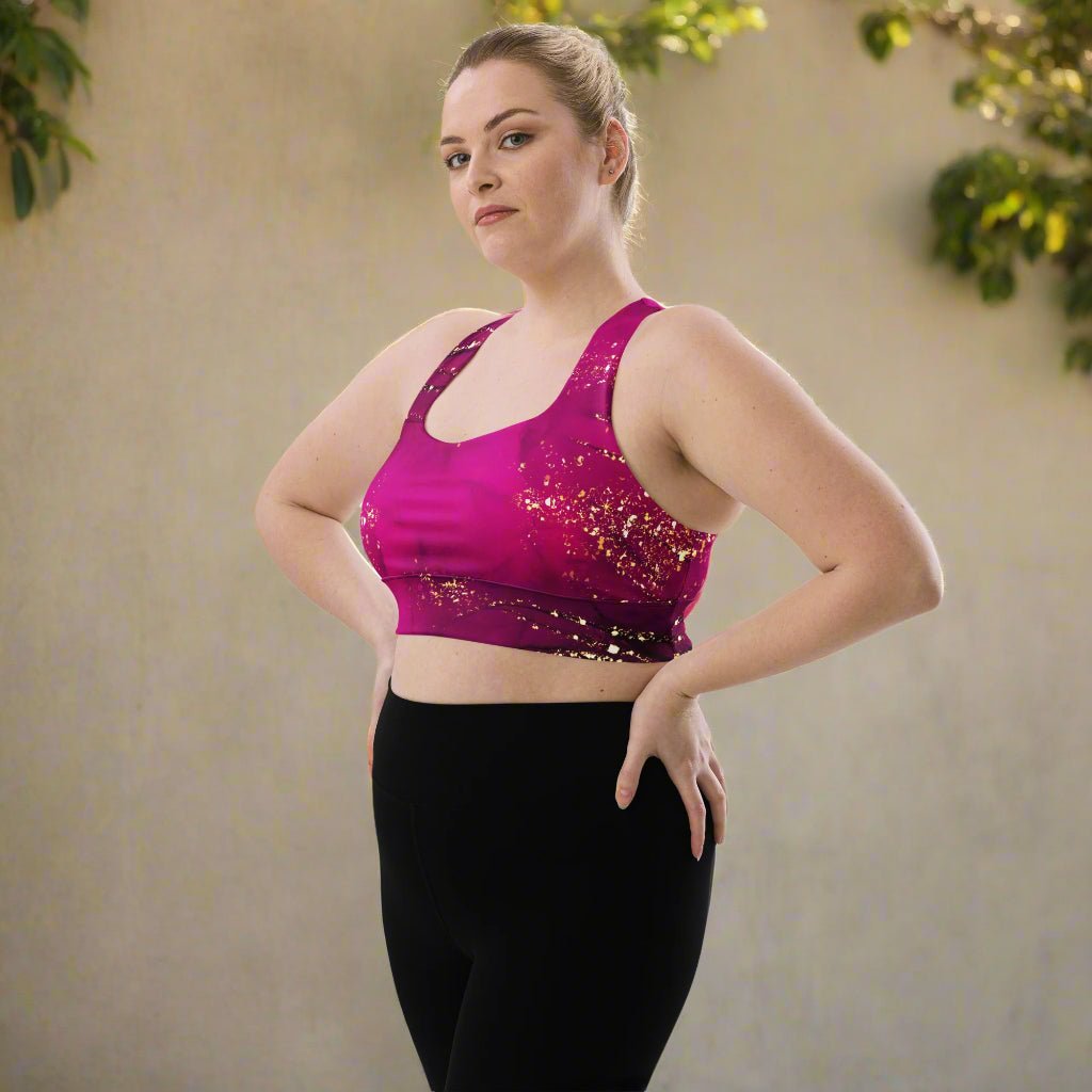 Woman wearing a pink sports bra and black leggings against a neutral background