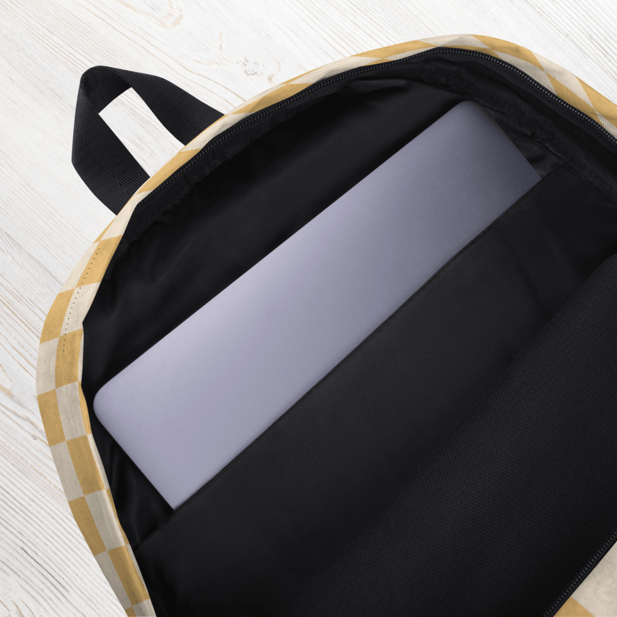 Open backpack with a laptop inside on a light wooden surface