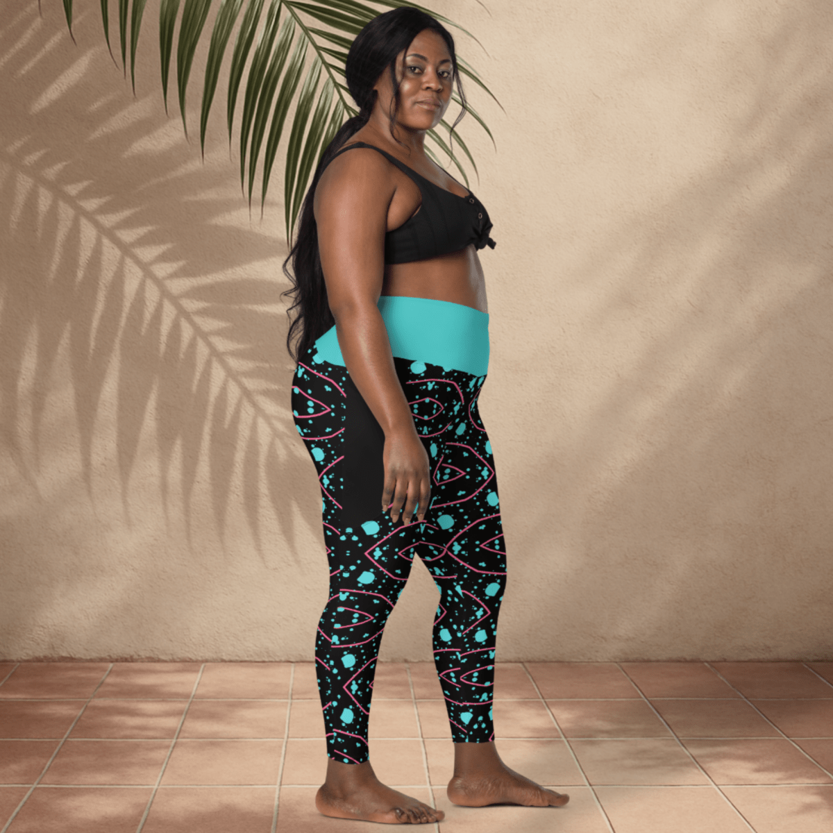 Woman wearing black and teal patterned leggings with a plain background