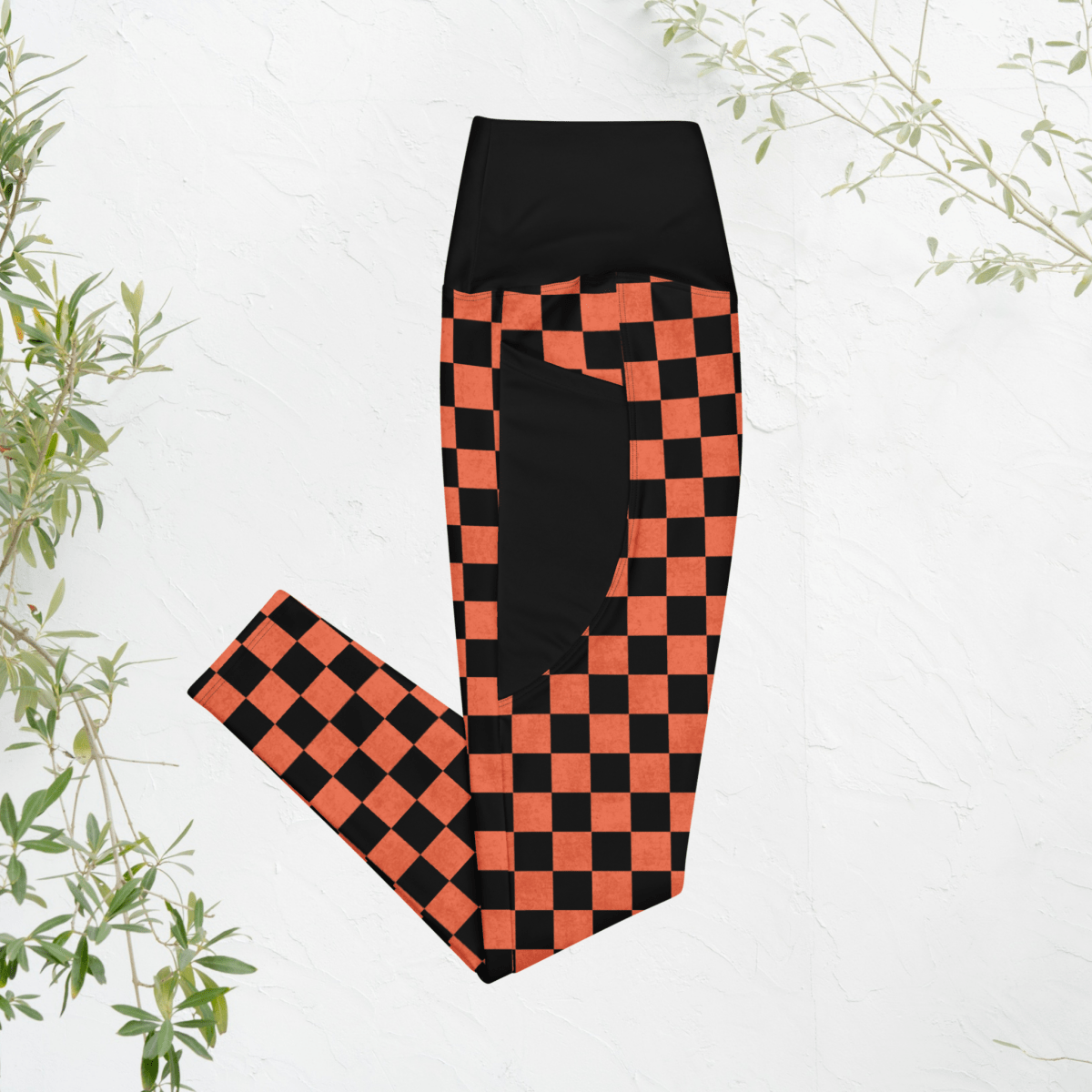 Black and orange checkered leggings on a white background with green leaves.