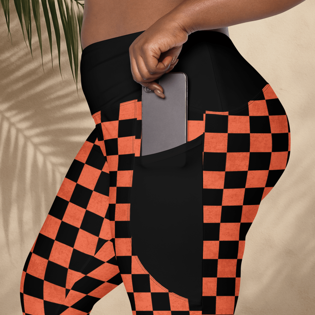 Person wearing black and orange checkered pants with a pocket, holding a phone.