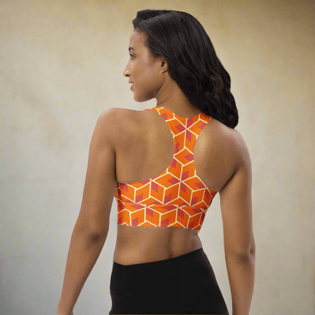 Woman wearing an orange geometric-patterned sports bra on a neutral background