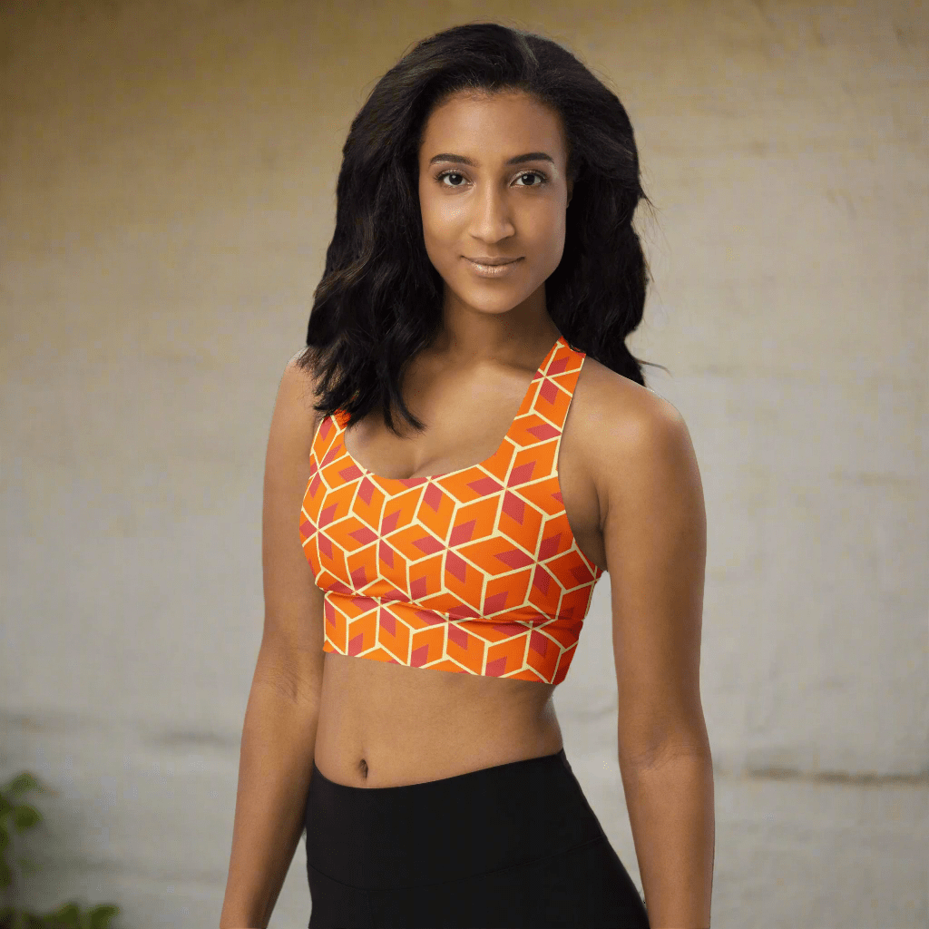 Woman wearing an orange geometric patterned sports bra on a neutral background