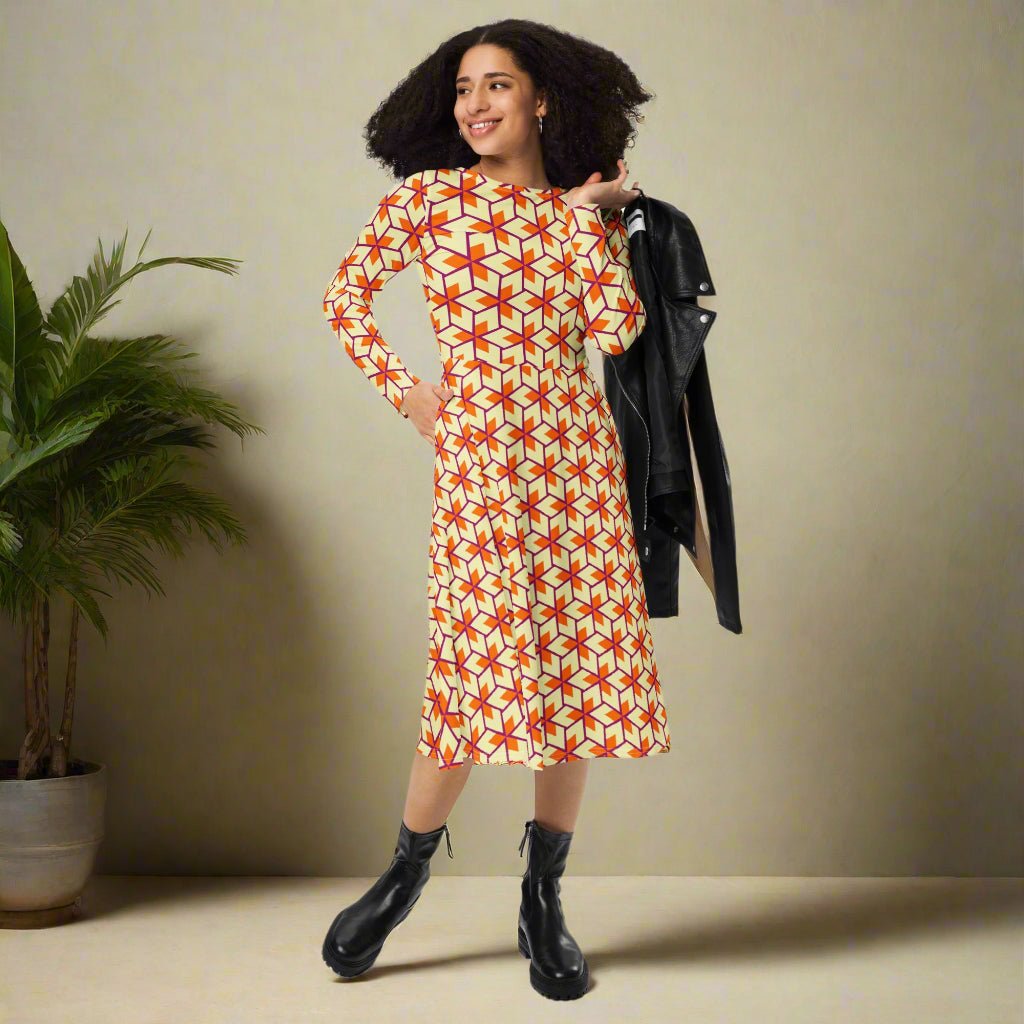 Woman wearing a geometric patterned dress holding a black jacket on a neutral background