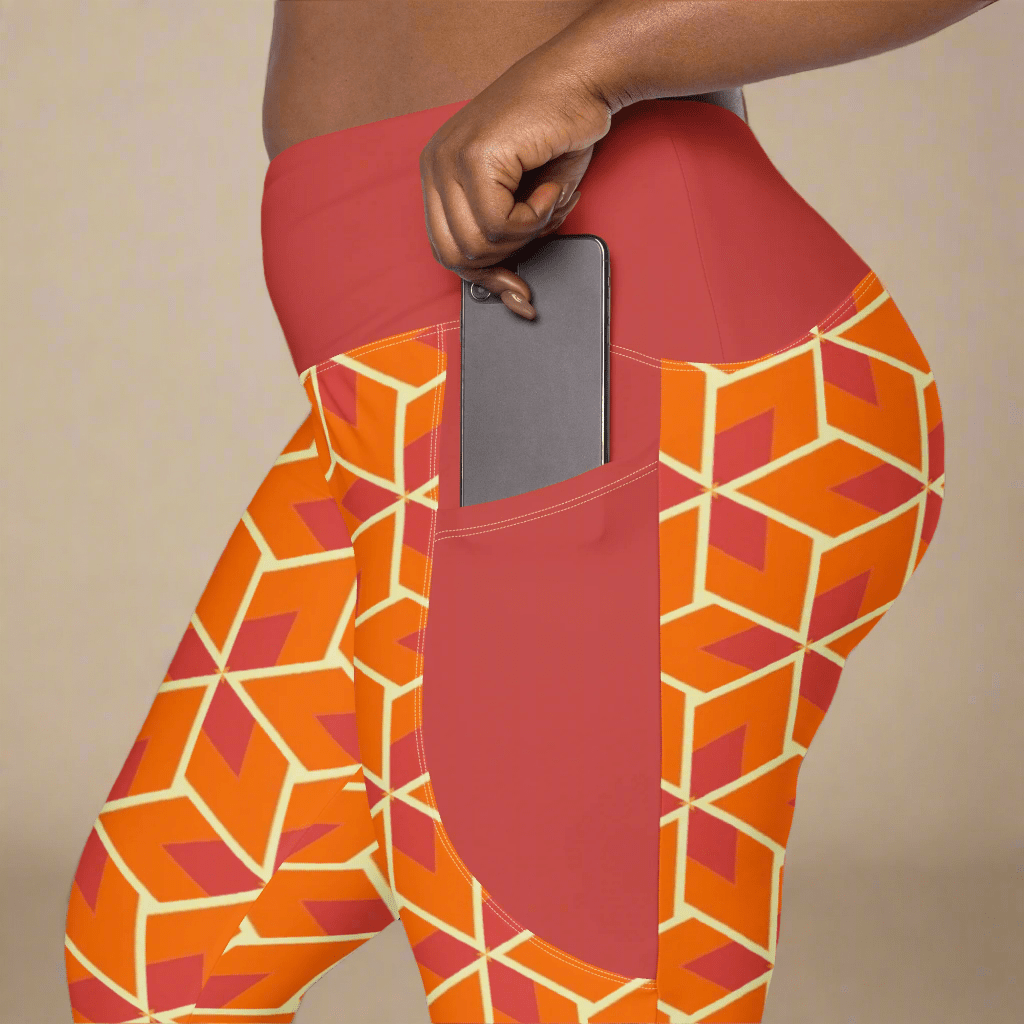 Orange geometric-patterned leggings with a pocket holding a phone on a beige background