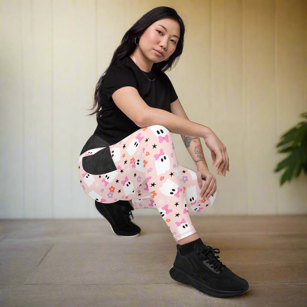 Person wearing a black top and colorful leggings with ghost and star pattern on a neutral background