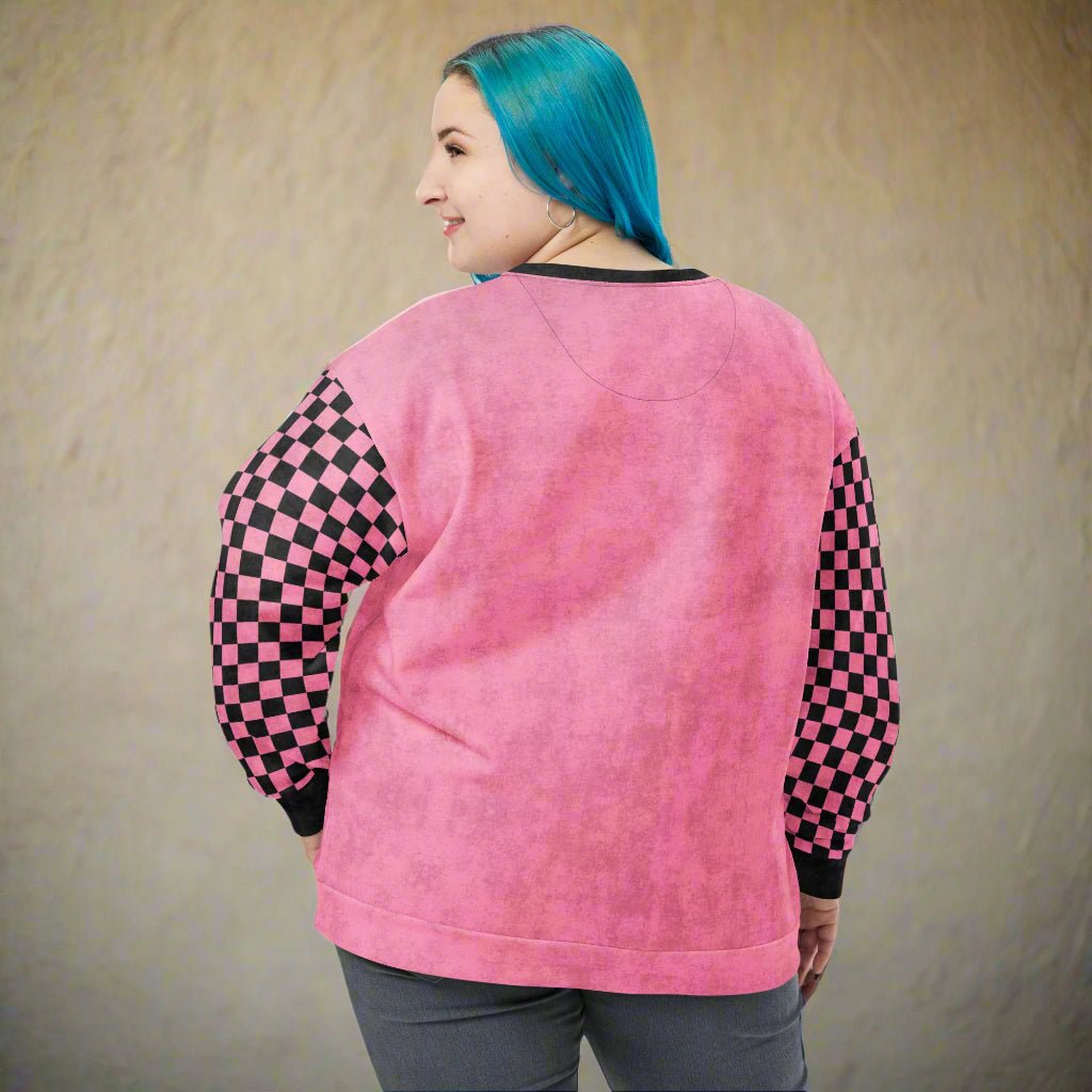 Person wearing a pink sweatshirt with checkered sleeves against a beige background