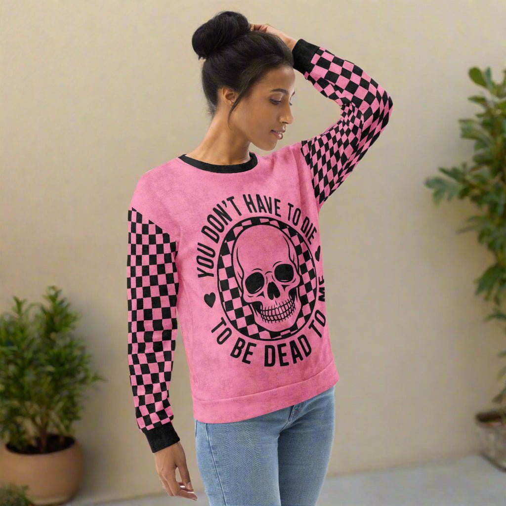 Person wearing a pink sweatshirt with a skull design and text on a white background