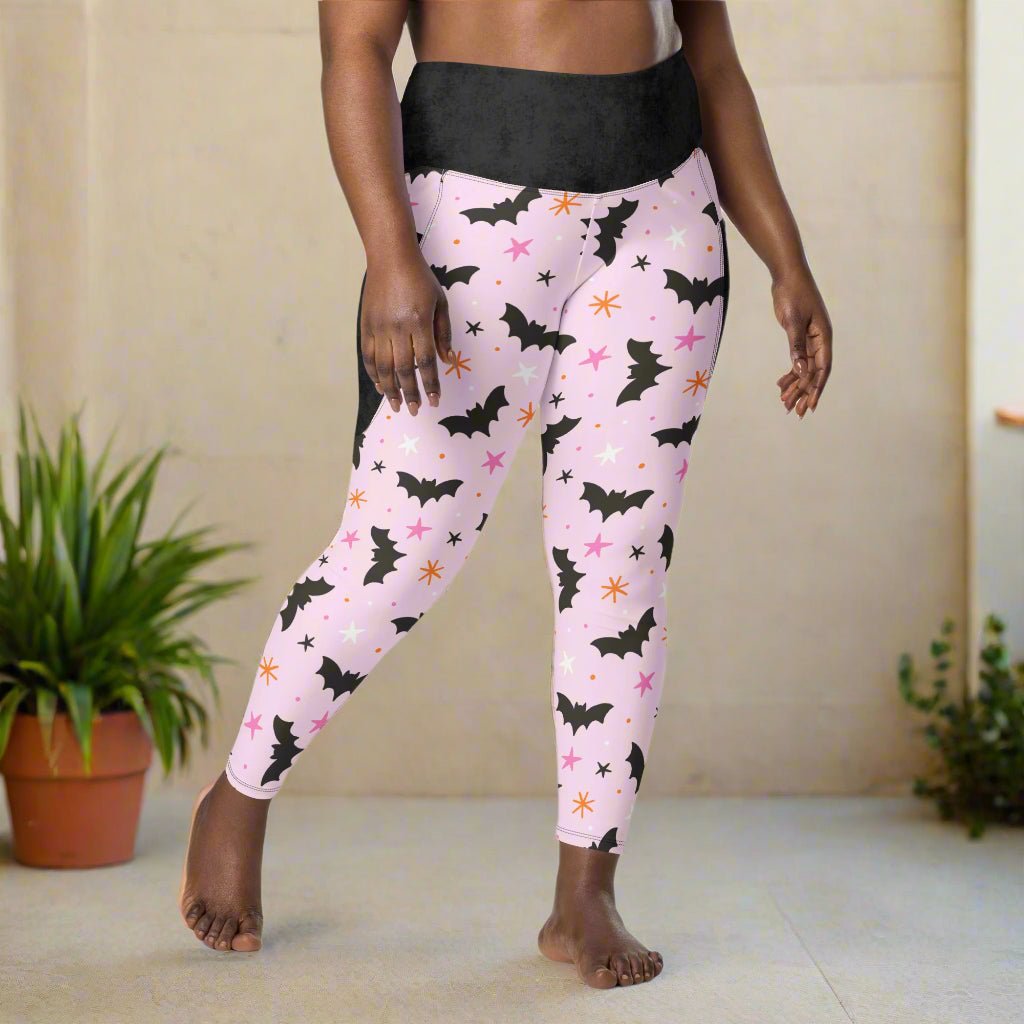 Pink leggings with black bat pattern worn by a person on a beige background