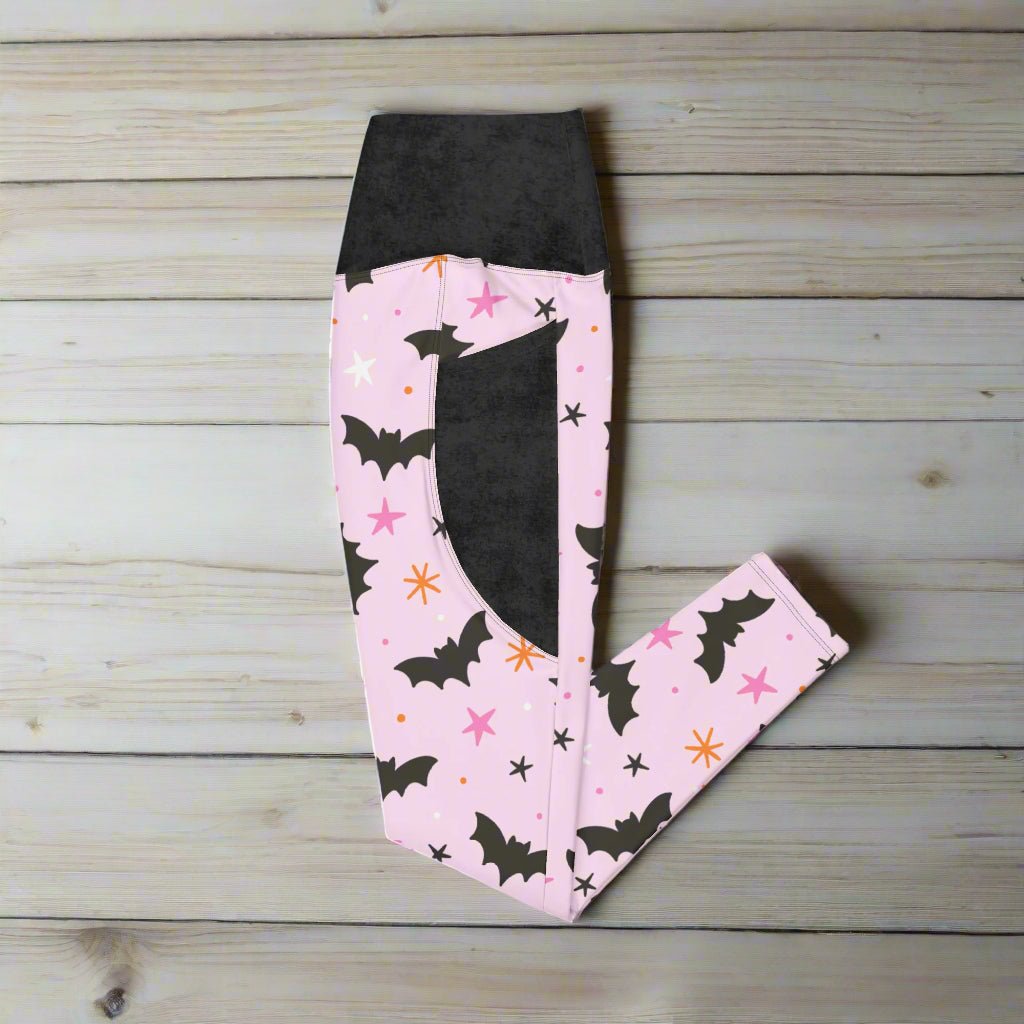 Pink leggings with black bat design on a wooden surface