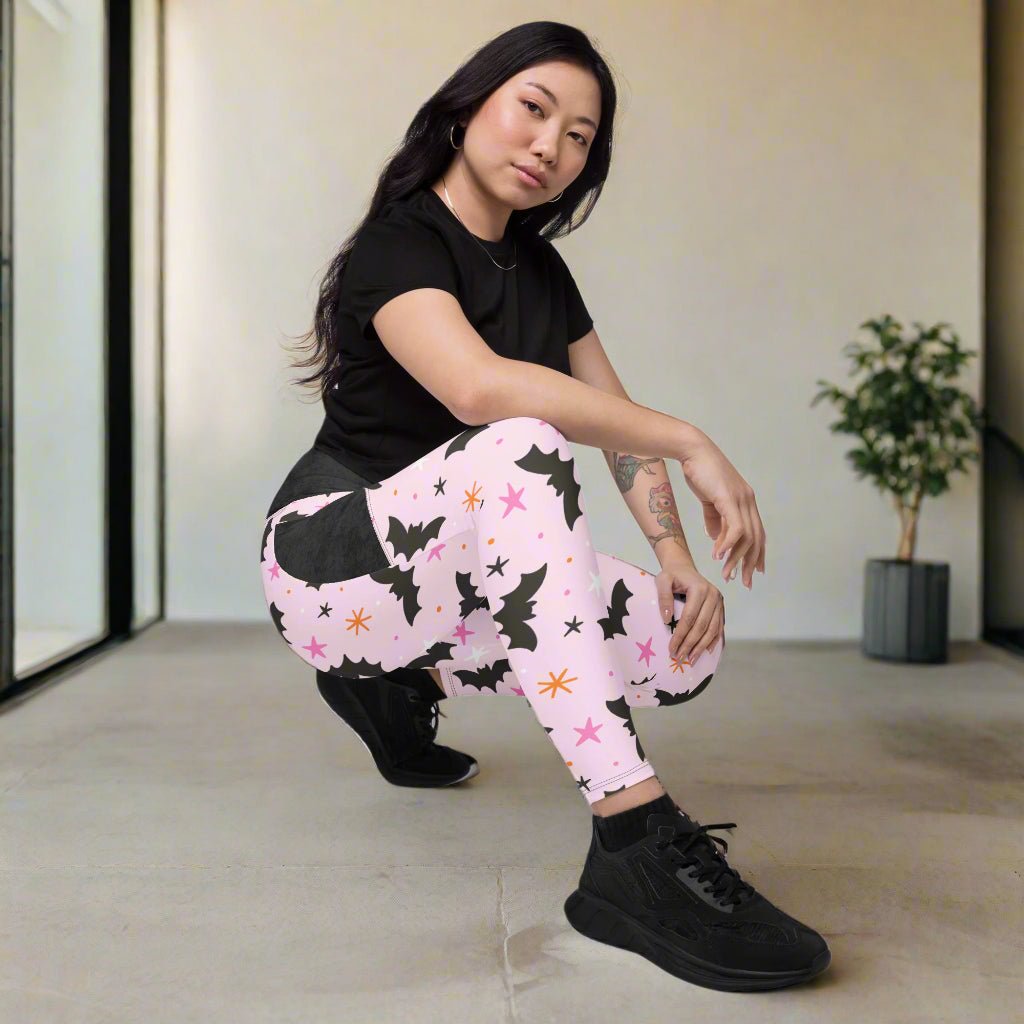 Person wearing pink leggings with black bat pattern in a room.