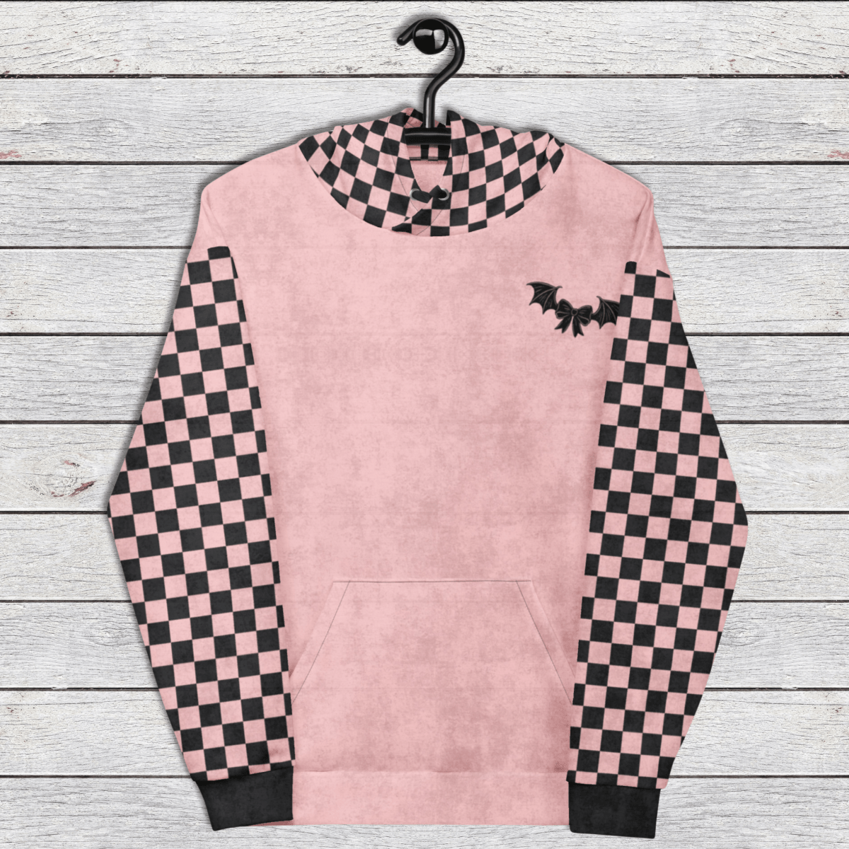 Pink hoodie with checkered sleeves and a bat design on a wooden background