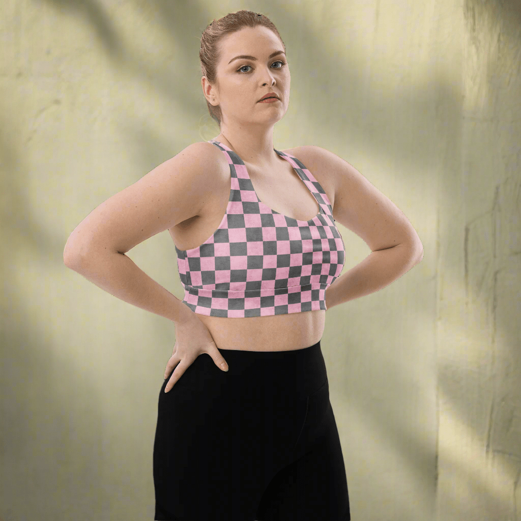 Person wearing a pink and gray checkered sports bra and black leggings on a white background