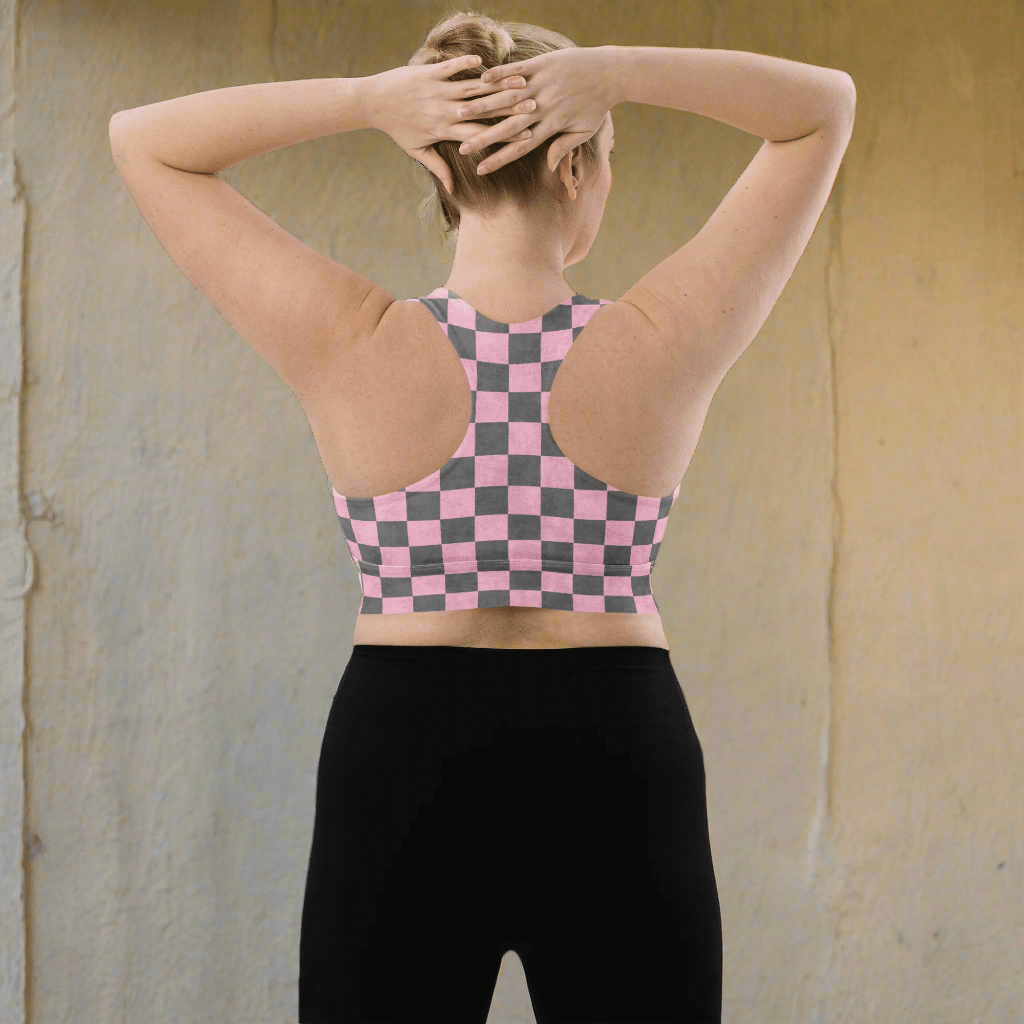 Person wearing a pink and gray checkered sports bra and black leggings on a neutral background