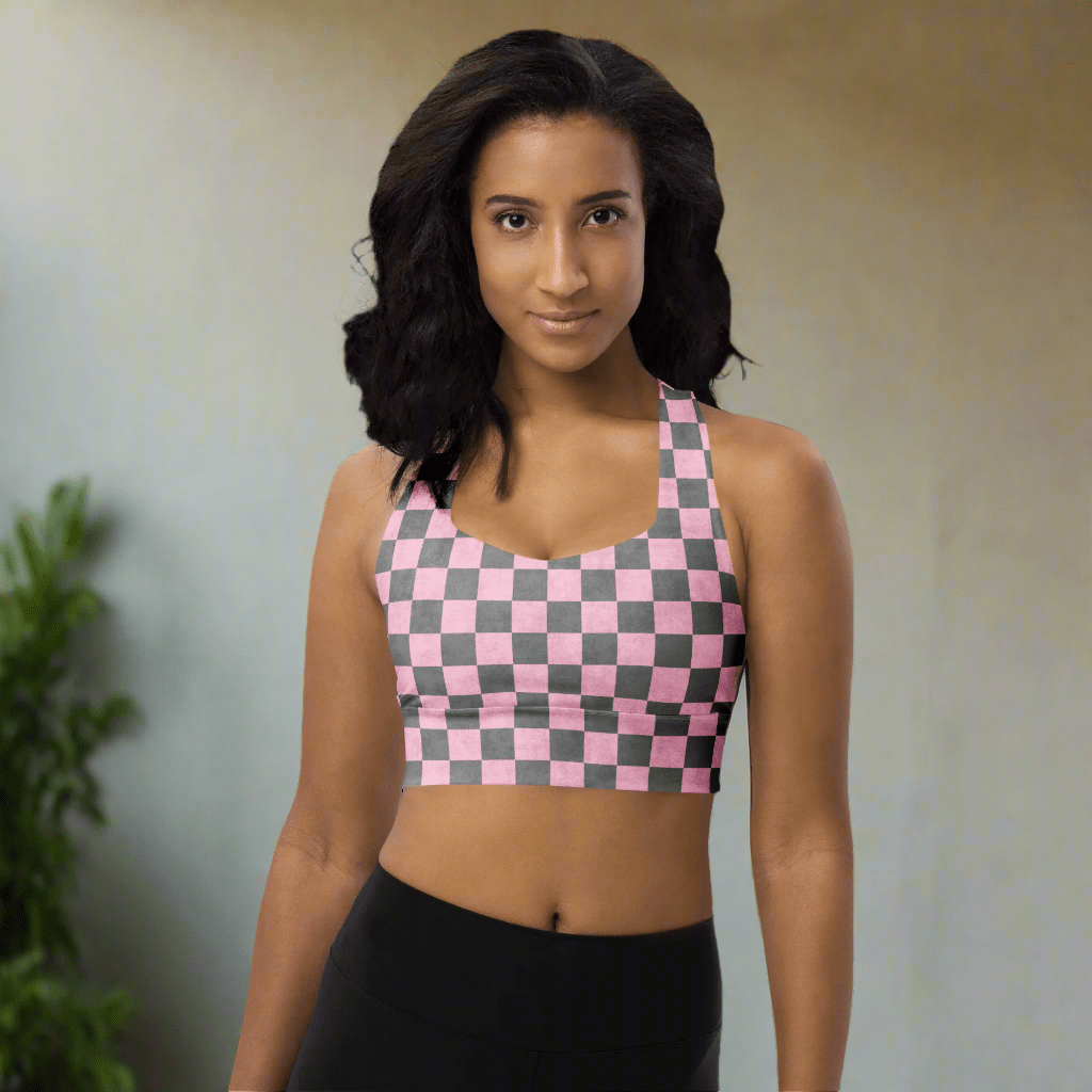 Woman wearing a pink and gray checkered sports bra on a neutral background