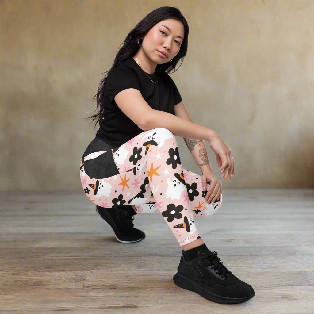 Woman wearing a black t-shirt and floral halloween leggings on a white background