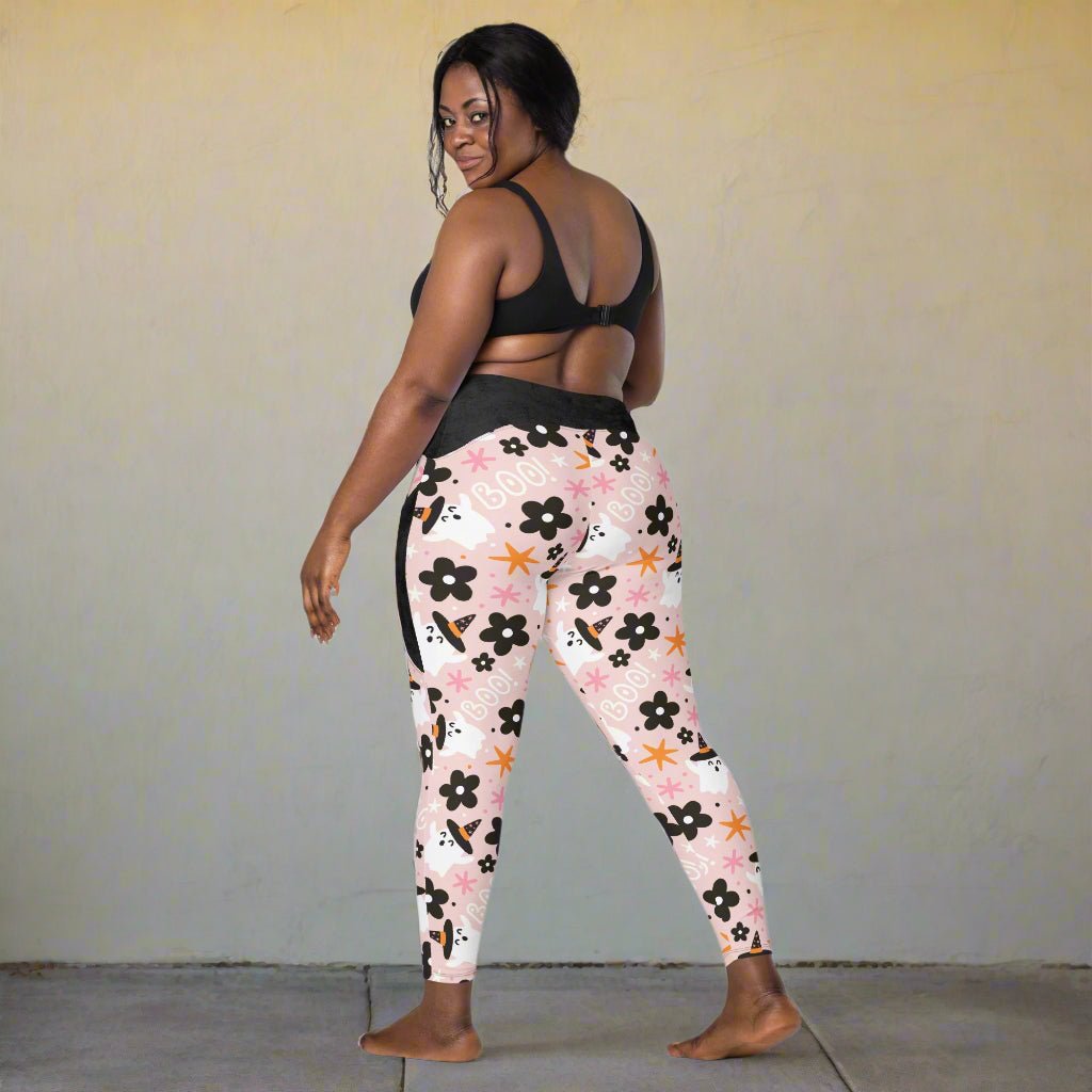 Woman wearing floral halloween leggings and a black sports bra on a white background