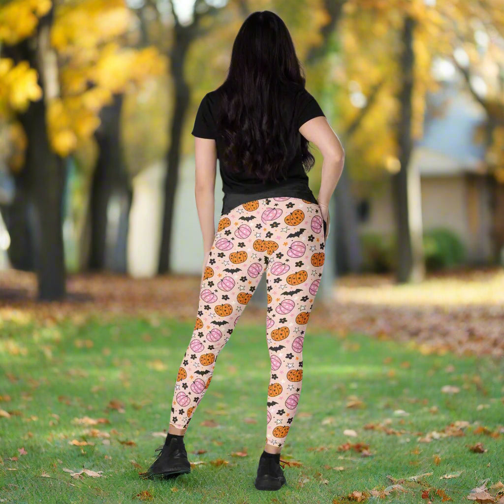 Person wearing pink leggings with Halloween-themed pattern on a neutral background