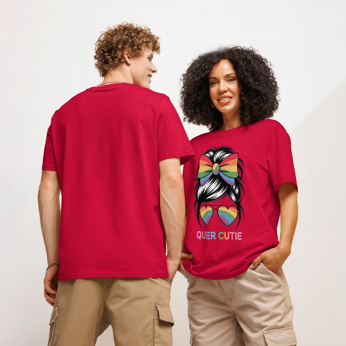 Two people wearing red t-shirts, one plain and one with a colorful design and text.