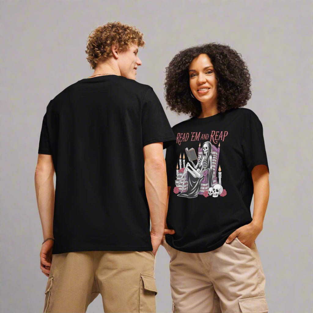 Models wearing a black tee featuring a lounging skeleton draped in a striped cloak, book in hand, surrounded by candles, roses, and a perfectly placed skull. “Read ’Em and Reap” tops the design in gothic lettering, making this shirt the ultimate pick for spooky season readers, goth-lit fans, and bookish baddies alike. One is facing towards the back showing the fit and length from behind