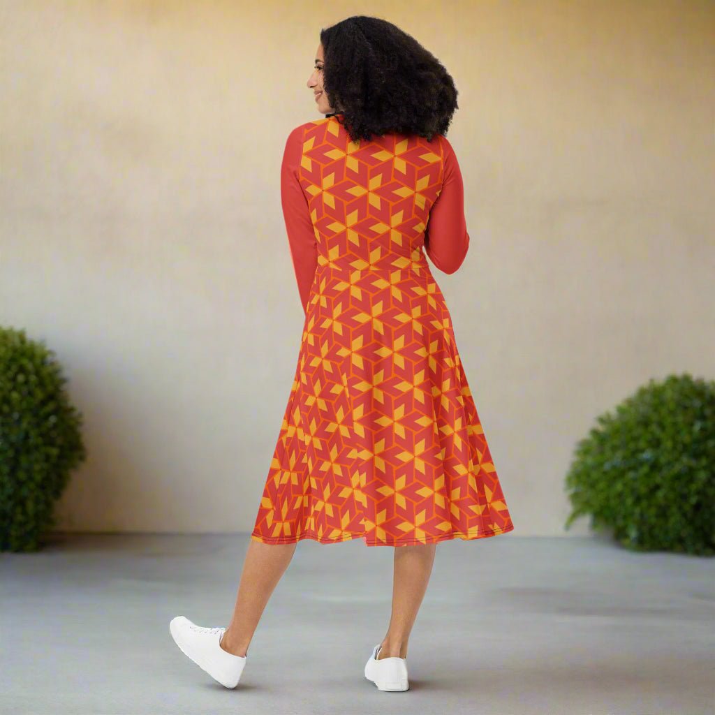 Woman wearing a red and yellow patterned dress standing in a minimal outdoor setting.