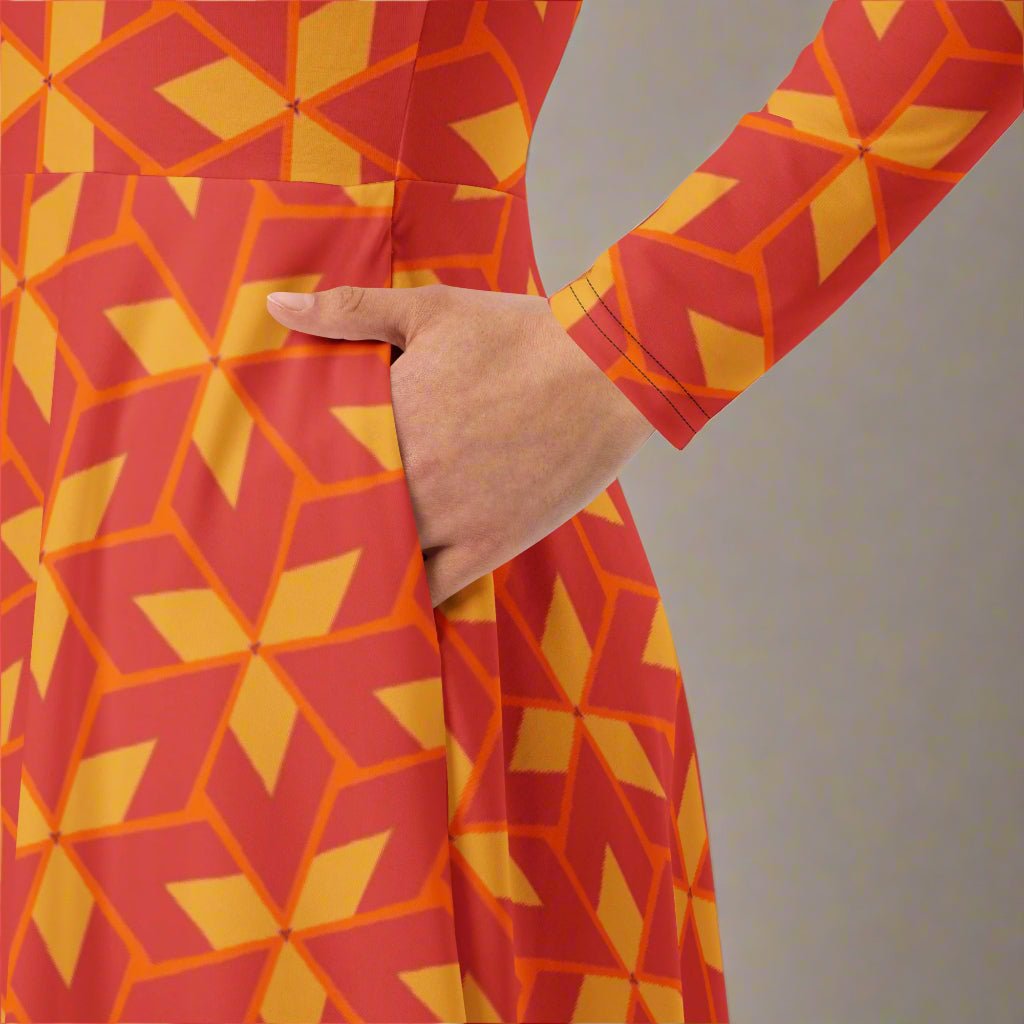 Red and yellow geometric patterned dress with a hand in pockets on a gray background