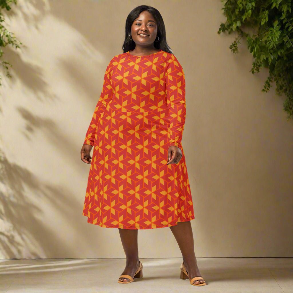 Woman wearing a red and yellow patterned dress standing against a beige wall with greenery.