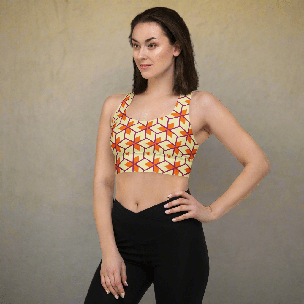 Woman wearing a geometric patterned sports bra and black leggings on a neutral background