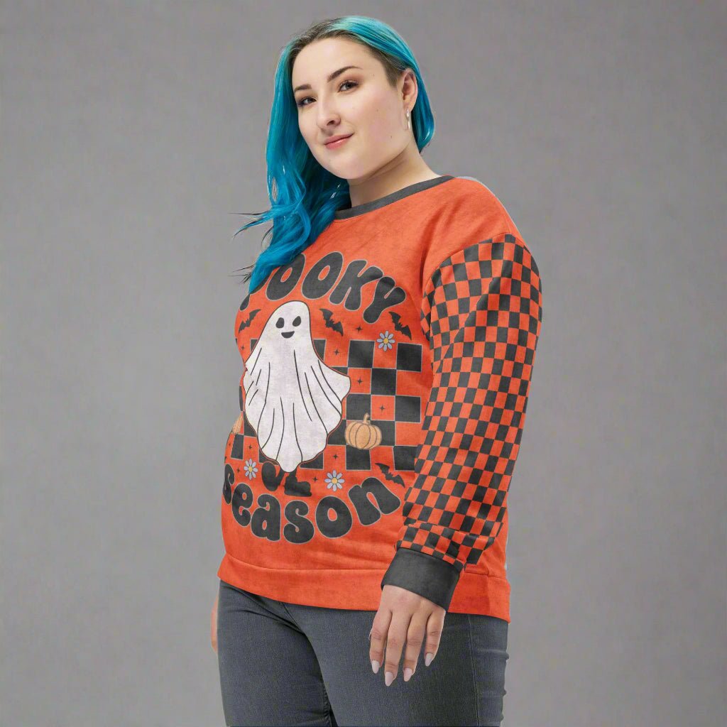 Person wearing a Halloween-themed orange sweatshirt with ghost and checkered pattern.