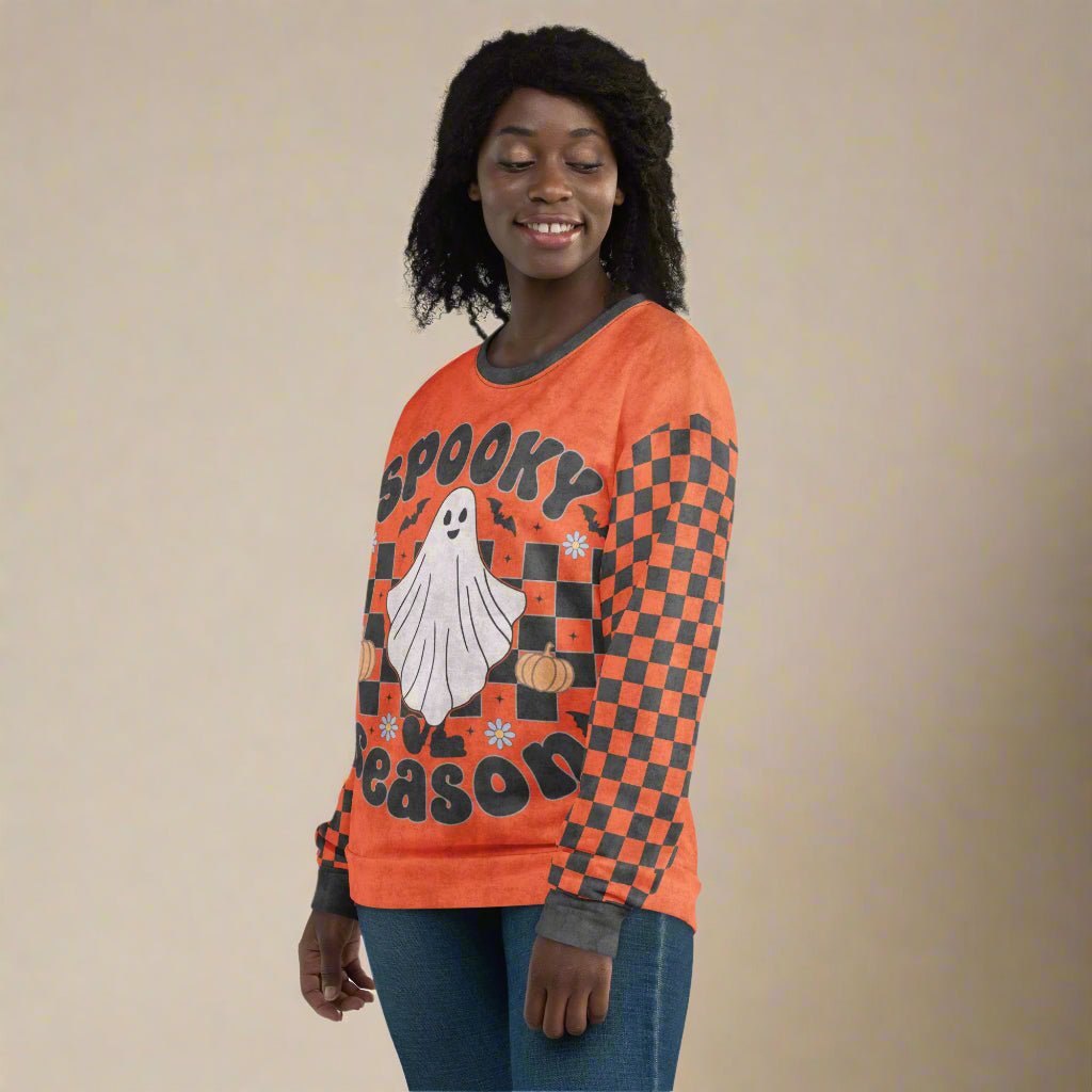 Person wearing an orange Halloween-themed sweater with a ghost and checkered pattern.