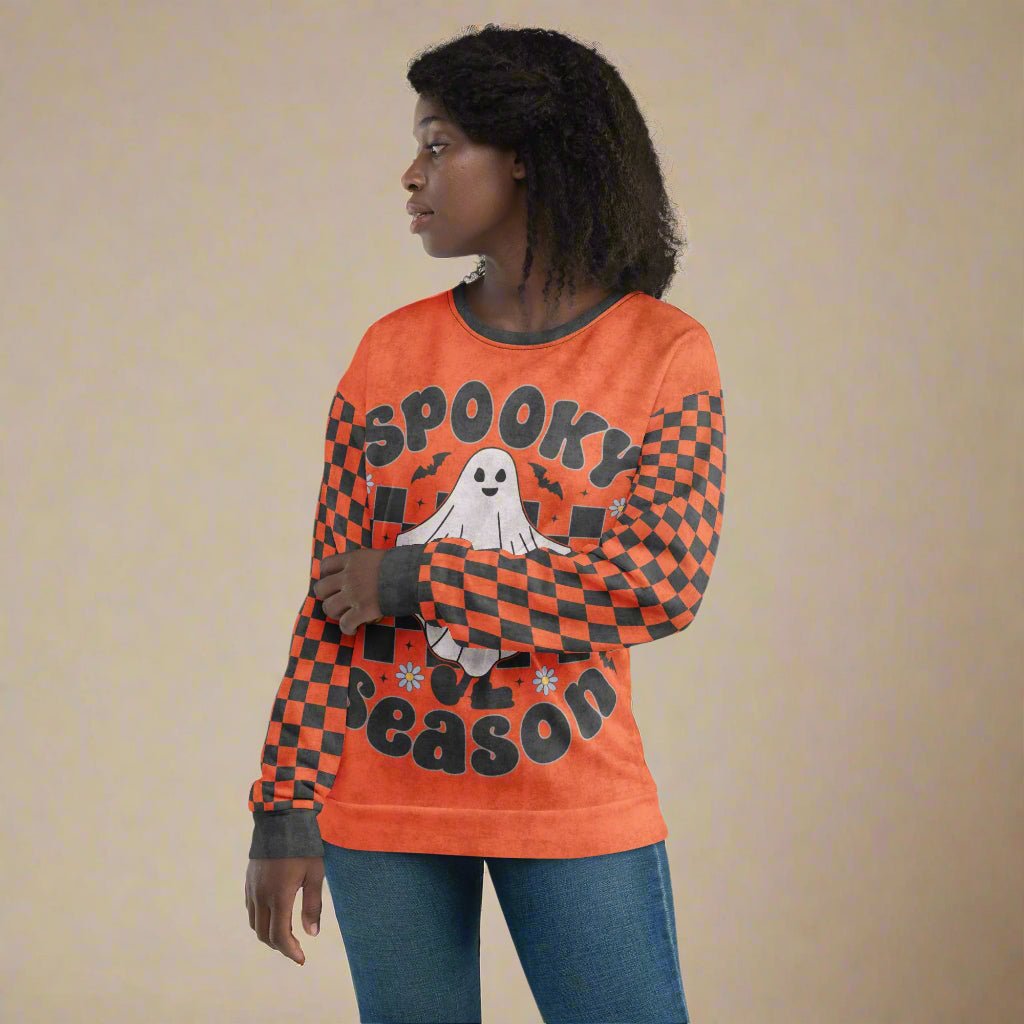 Person wearing an orange Halloween-themed long-sleeve shirt with a ghost and checkered pattern.