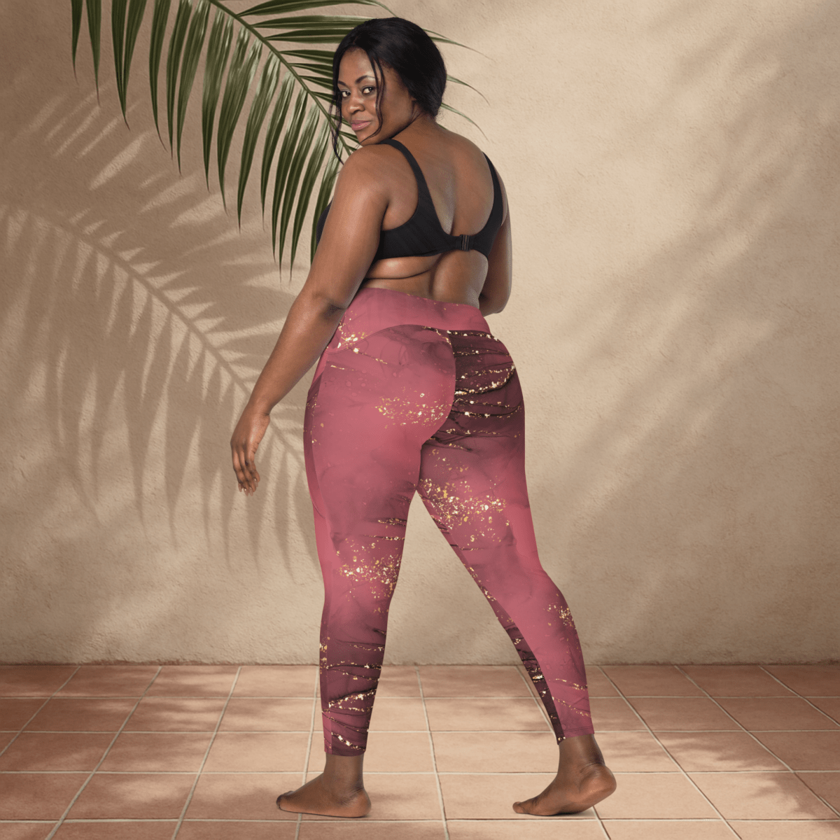 Woman wearing dusty rose marble leggings with golden accents against a beige wall.