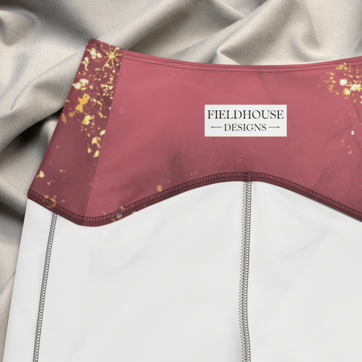 Close-up of a garment with 'Fieldhouse Designs' label against a neutral background
