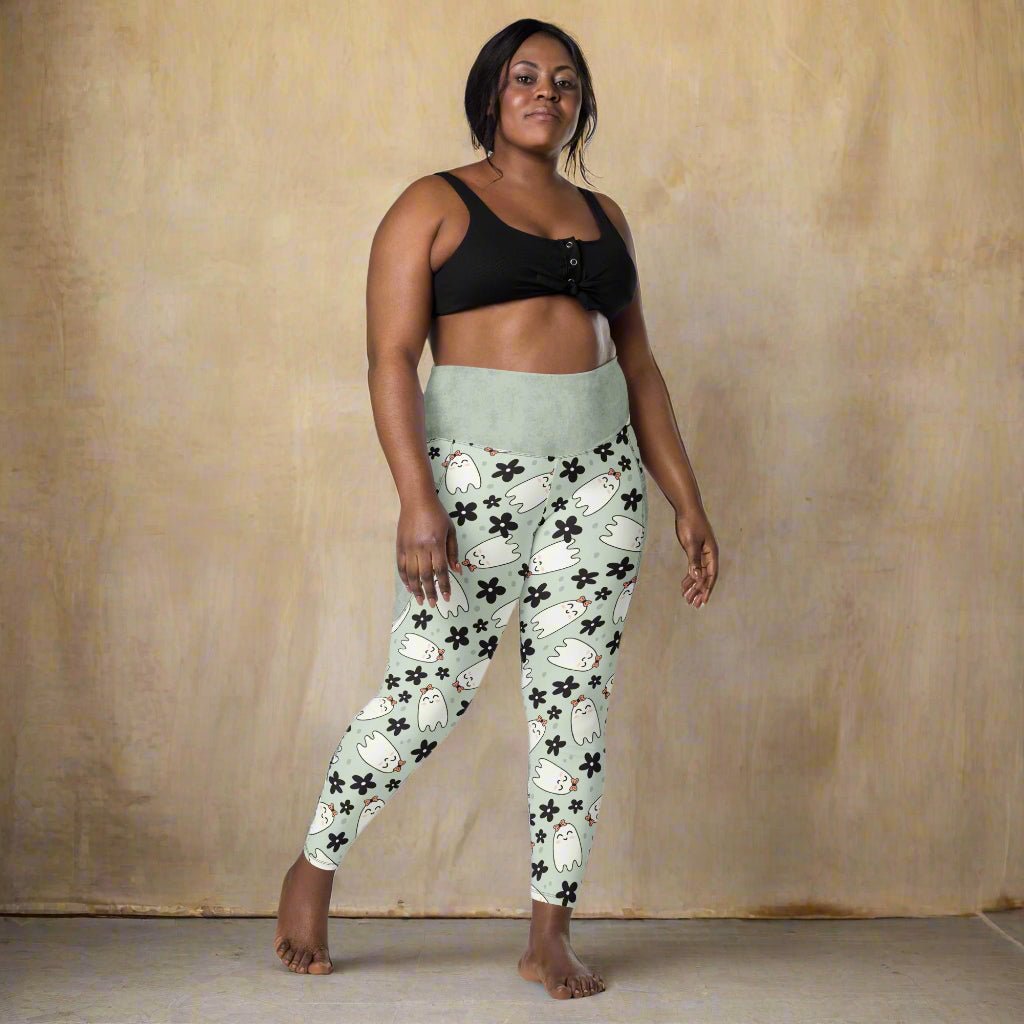 Woman wearing a black sports bra and halloween leggings on a white background