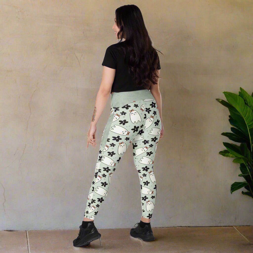 Woman wearing light green leggings with ghost and flower pattern on a beige background