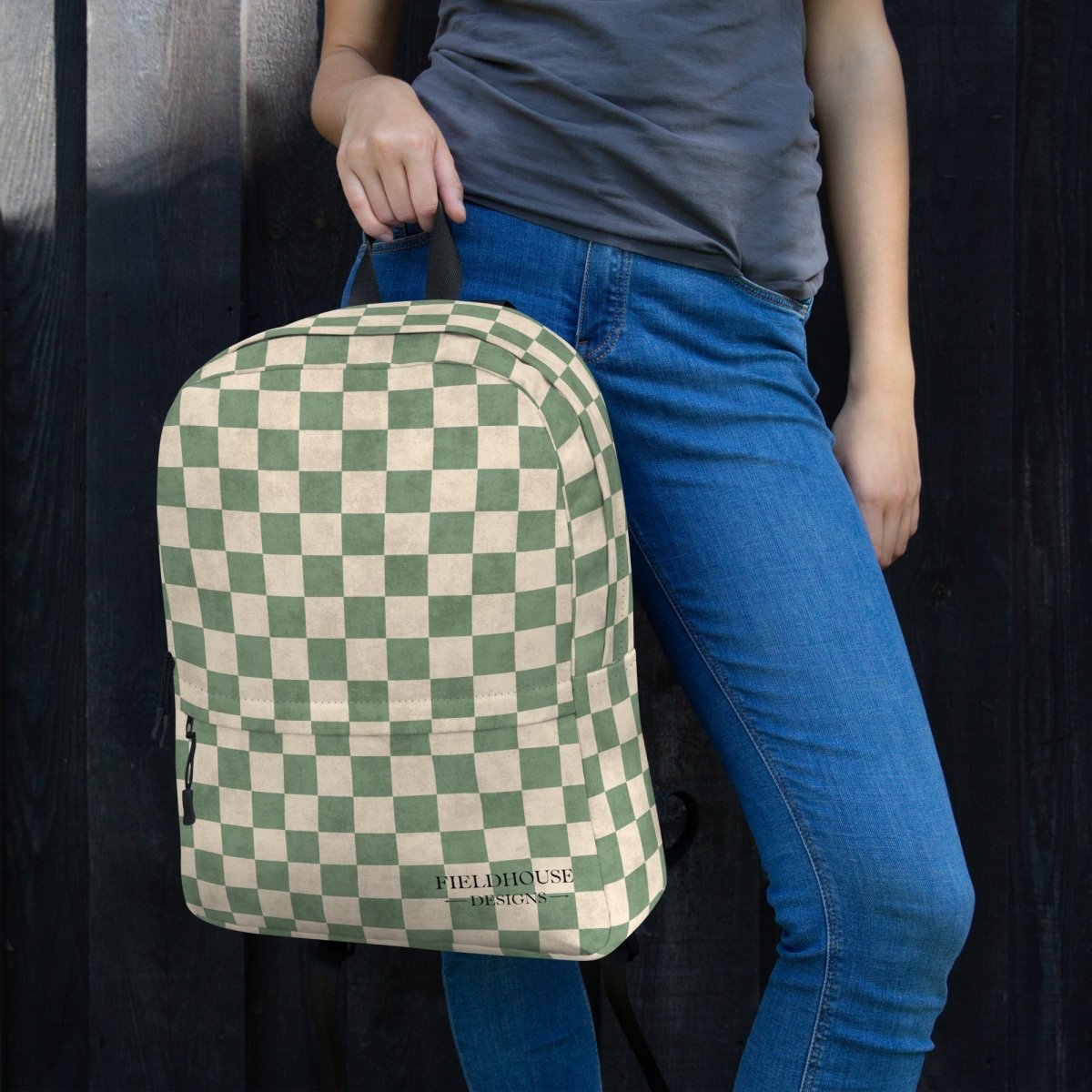 Person holding a green and beige checkered backpack with 'Fieldhouse Designs' branding.